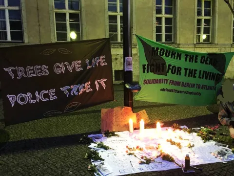 two banners from berlin's vigil for comrade tort, reading "trees saves life, police take it" and "mourn the dead, fight fo the living"